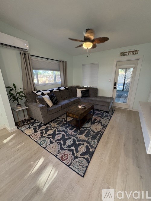 A living room with a couch, a rug, and a ceiling fan.