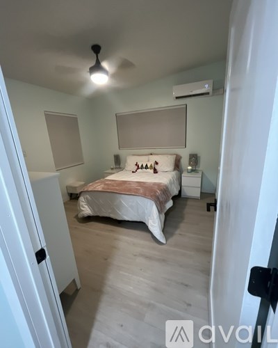 A bedroom with a bed, nightstand, and window.