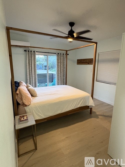 A bedroom with a bed, a ceiling fan, and a window with curtains.