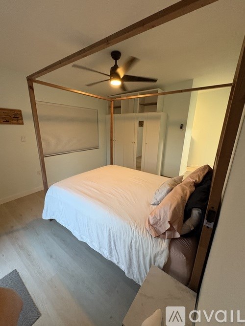 A bedroom with a bed, a ceiling fan, and a mirror.