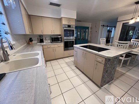 A kitchen with a white countertop and a black stove top.