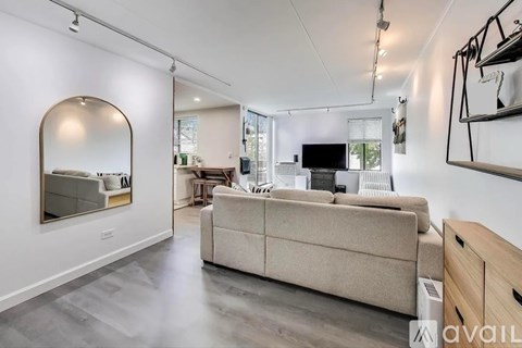 A spacious living room with a beige sofa and a large mirror on the wall.
