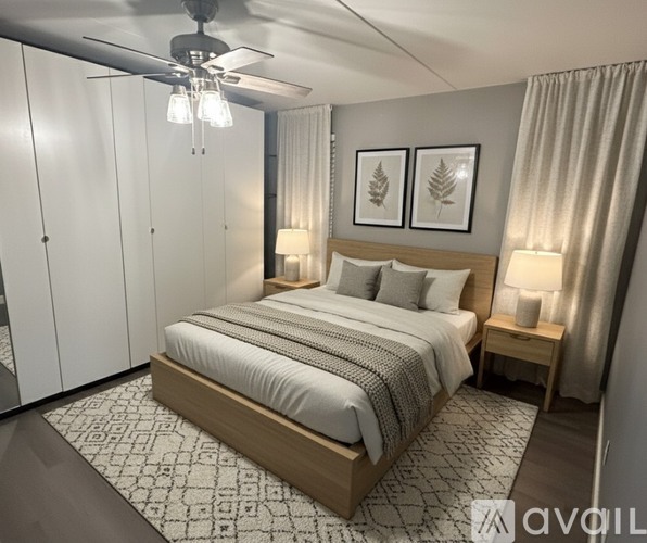 A bedroom with a large bed, a ceiling fan, and two framed leaves on the wall.