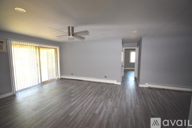 A spacious room with a ceiling fan and sliding glass doors.