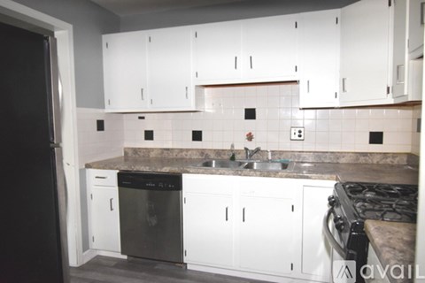 A kitchen with white cabinets and a black refrigerator.