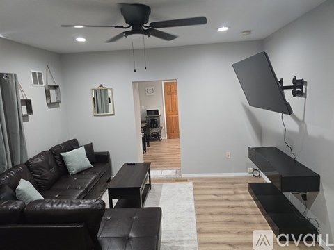 A living room with a black leather couch and a television.
