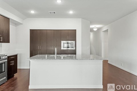 A modern kitchen with dark brown cabinets and a white island.