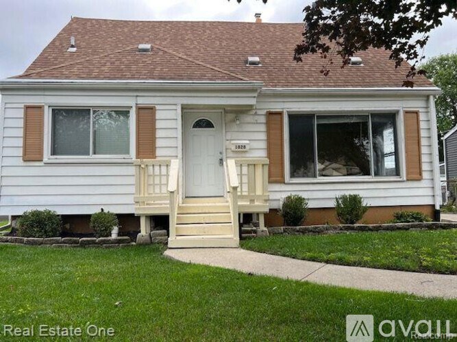 A white house with a brown roof and a porch.