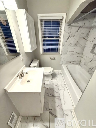 A bathroom with a marble floor and white walls.