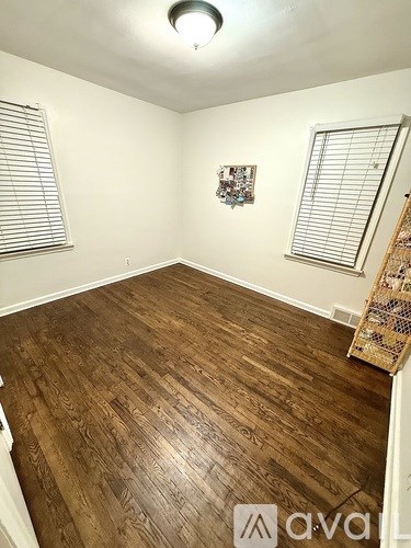 A room with wooden flooring and a window with blinds.