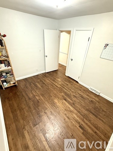 A room with wooden flooring and three doors.
