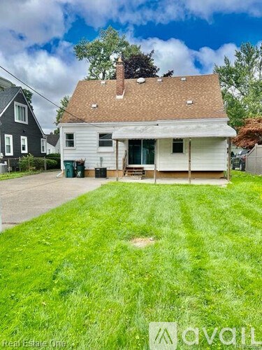 A white house with a brown roof and a green lawn in front.