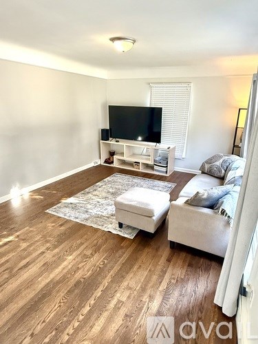 A living room with a white couch, a television, and a rug.