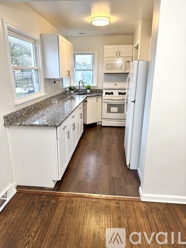 A kitchen with white cabinets and a granite countertop.