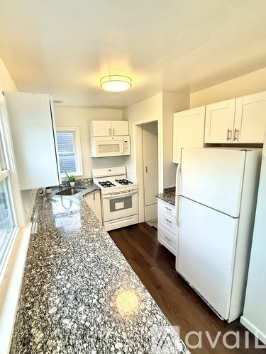 A kitchen with granite countertops and white appliances.