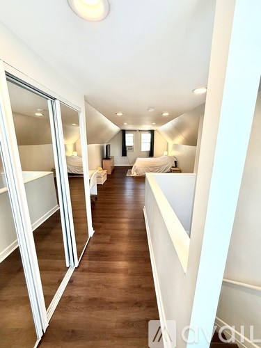 A long hallway with white walls and wood floors.
