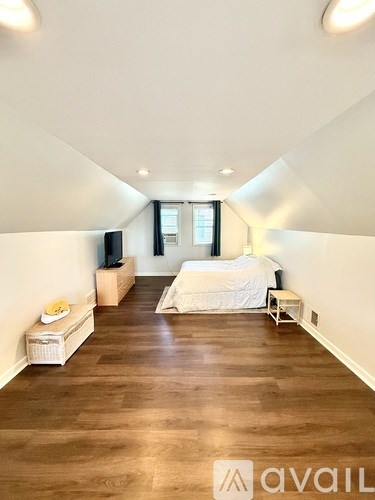 A bedroom with a bed, nightstand, and window.