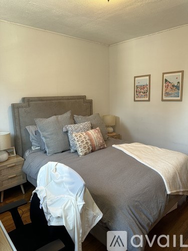 A bedroom with a bed, nightstand, and two pictures on the wall.