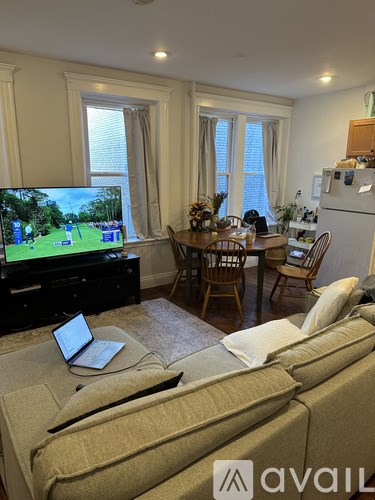 A living room with a couch, a television, a dining table, and chairs.