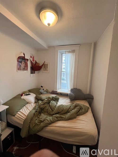 A bedroom with a bed covered in a green blanket.