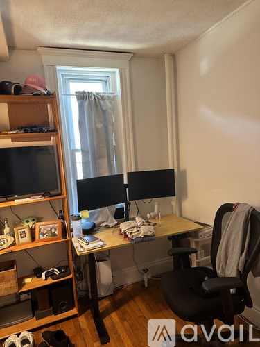 A room with a desk, chair, and computer monitors.