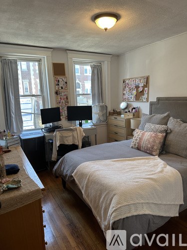 A bedroom with a bed, desk, and window.