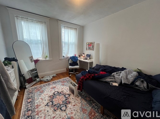 A bedroom with a bed, a desk, and a rug.