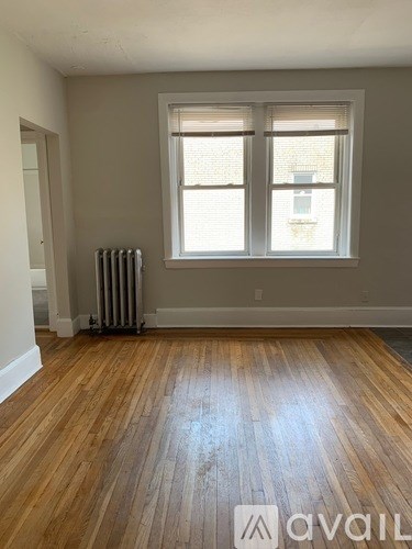 A room with wooden floors and a window with blinds.