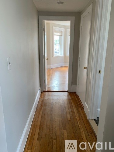 A hallway with wood floors and white walls.
