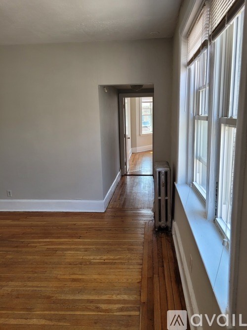 A room with wooden floors and a window on the right side.