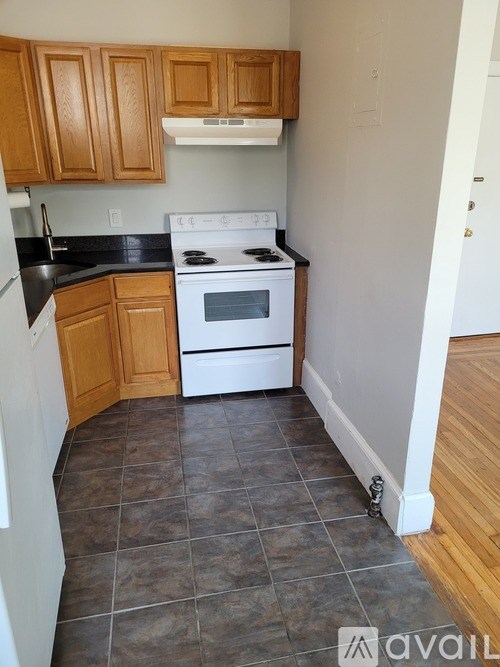 A kitchen with wooden cabinets and a white stove top oven.