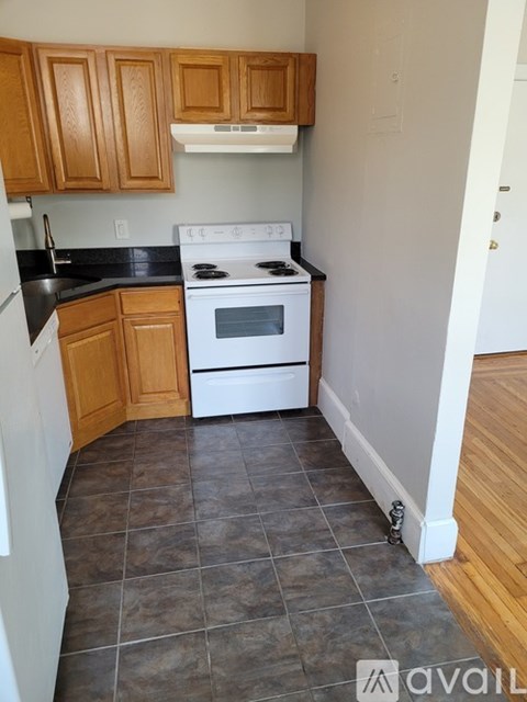 A kitchen with wooden cabinets and a white stove top oven.