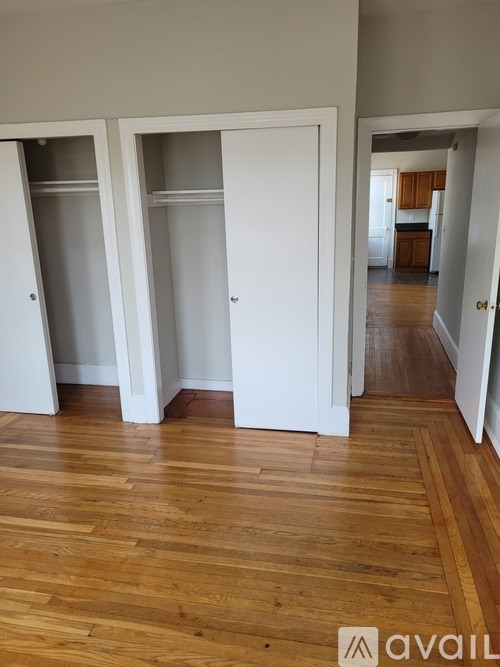 Three white doors are open in a room with wooden floors.