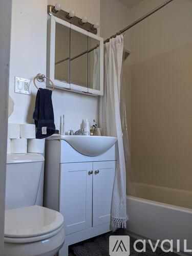A white bathroom with a toilet, sink, and mirror.