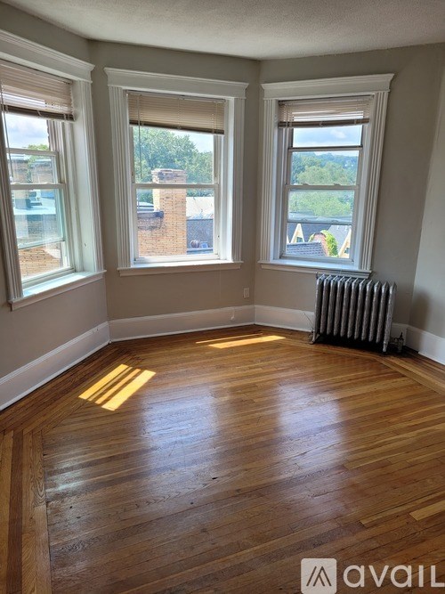 A room with wooden floors and three windows.