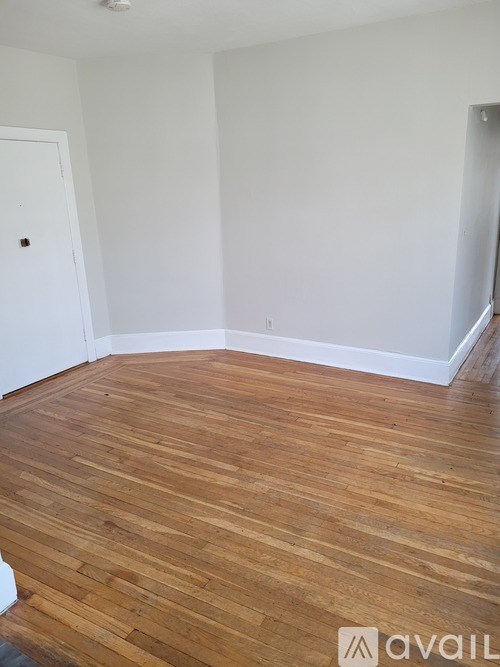 A room with wooden flooring and white walls.