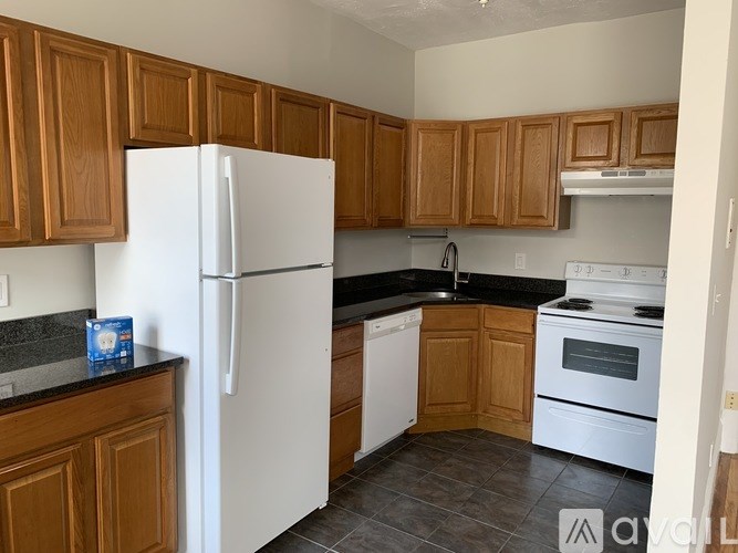A kitchen with white appliances and wooden cabinets.