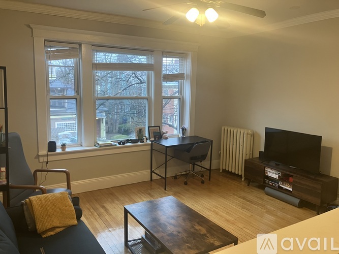 A living room with a blue couch, a coffee table, a television, and a window with a view of a city.