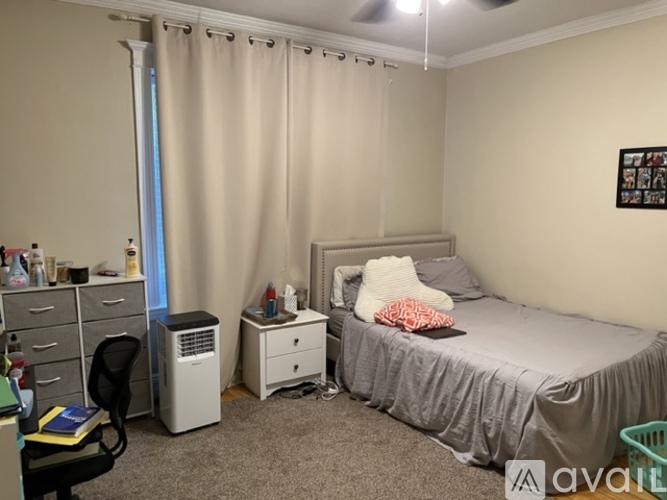 A bedroom with a bed, desk, chair, and window with curtains.