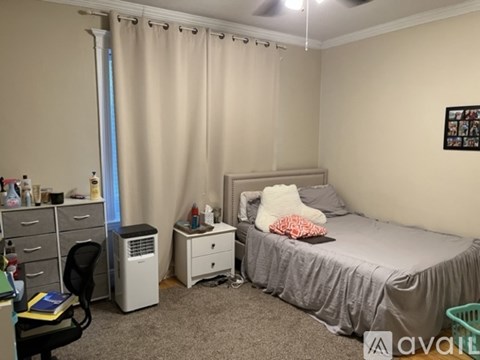 A bedroom with a bed, desk, chair, and window with curtains.