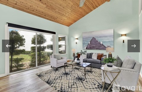 A living room with a couch, chairs, and a rug in front of a painting.