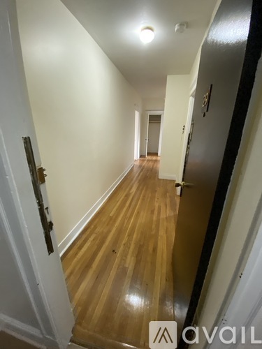 A hallway with wood floors and white walls.