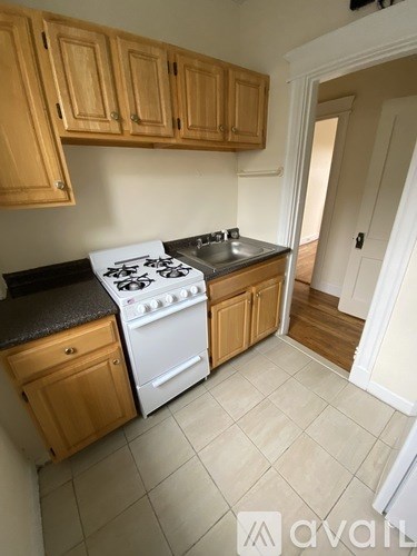 A kitchen with wooden cabinets and a white stove top oven.