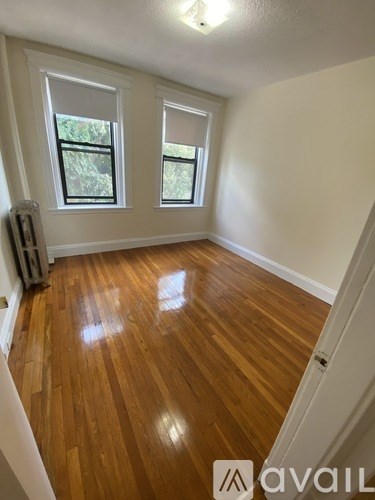 A room with wooden floors and two windows.