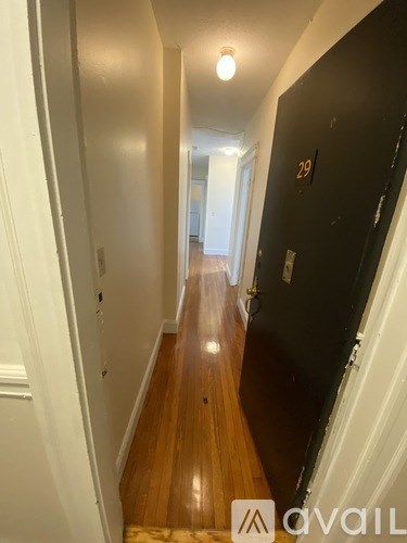 A hallway with a black door on the right and a white door on the left.