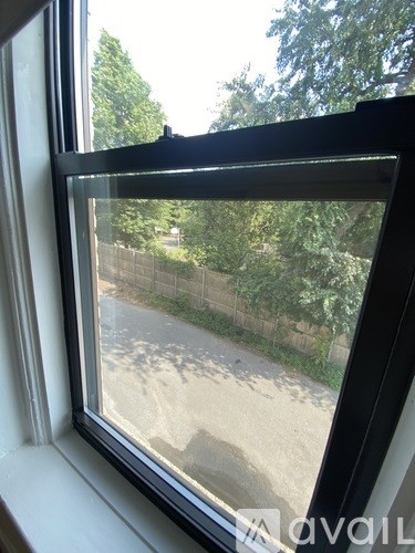A window with a view of a tree and a fence outside.