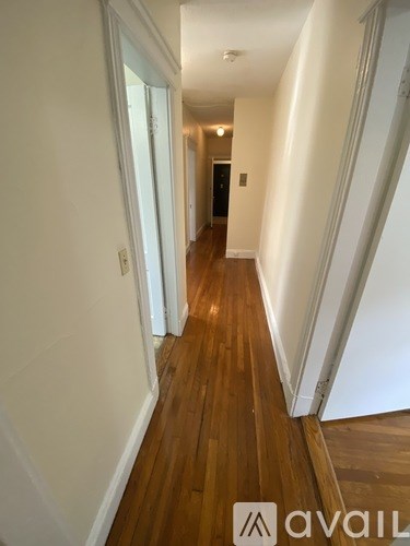 A hallway with wooden floors and white walls.