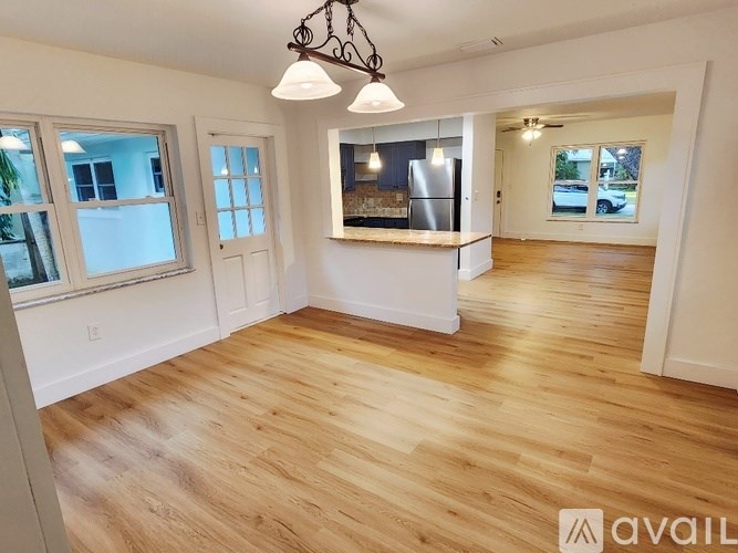 A spacious room with wooden flooring and a large window.