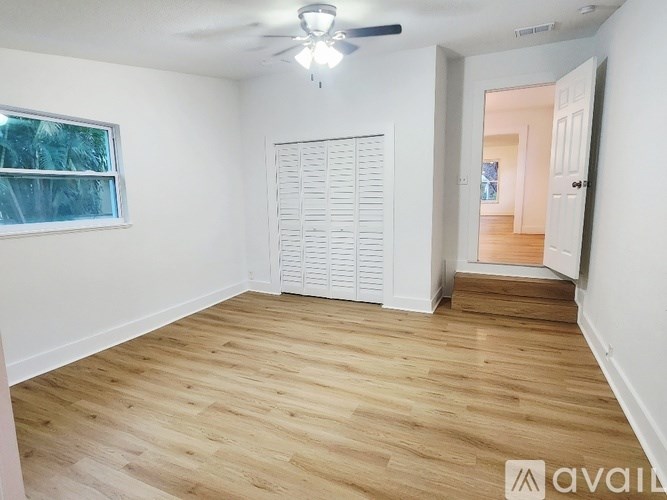 A room with wooden flooring and a window with blinds.