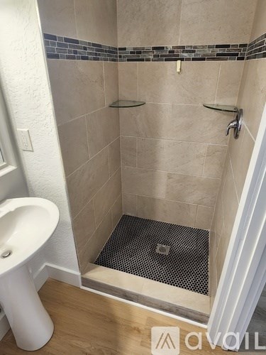 A white pedestal sink in a tiled shower.